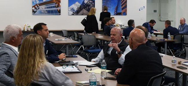 A group of advisors sits at a table, holding a discussion