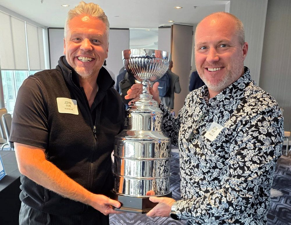 Two advisors stand together to hold the Cornerstone Cup