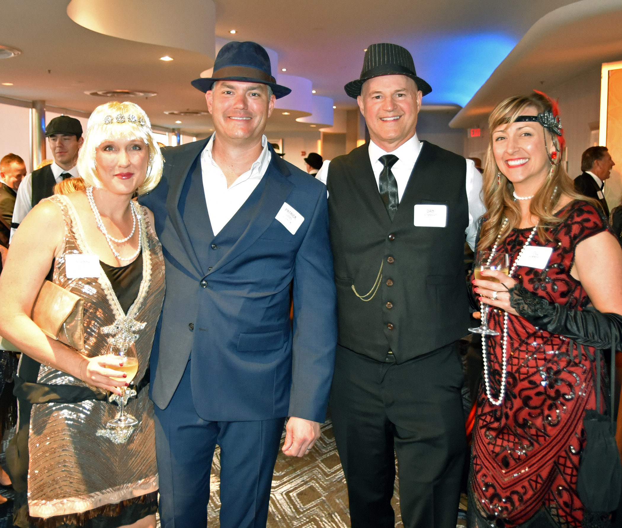 A group of people, dressed in 1920s attire, stand together at a party