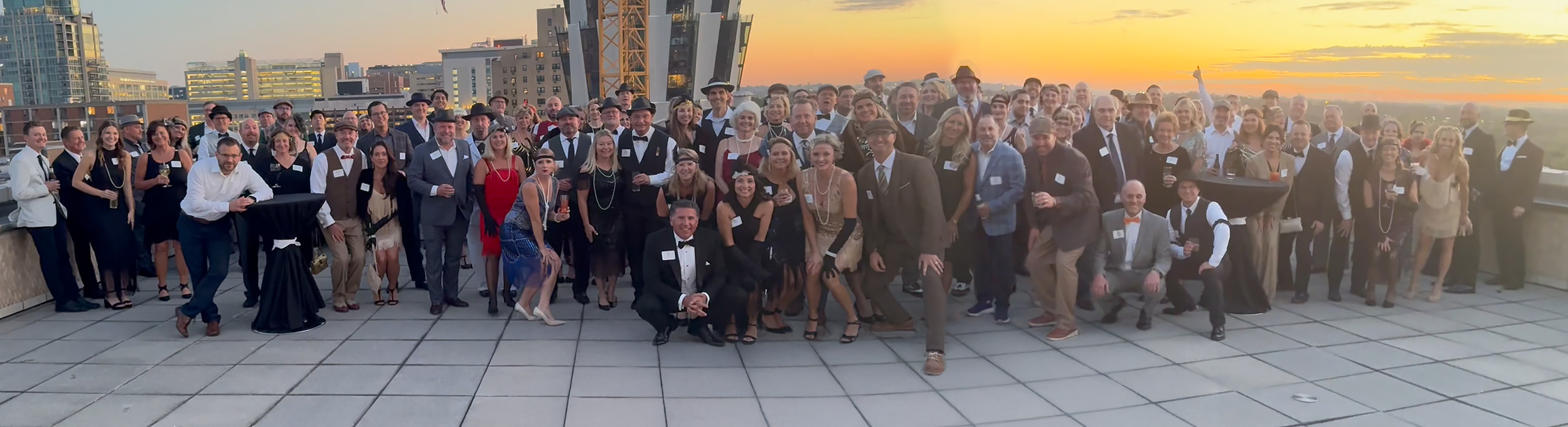 A group of partygoers stand outside together on a balcony