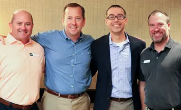 A group of advisors stand together smiling