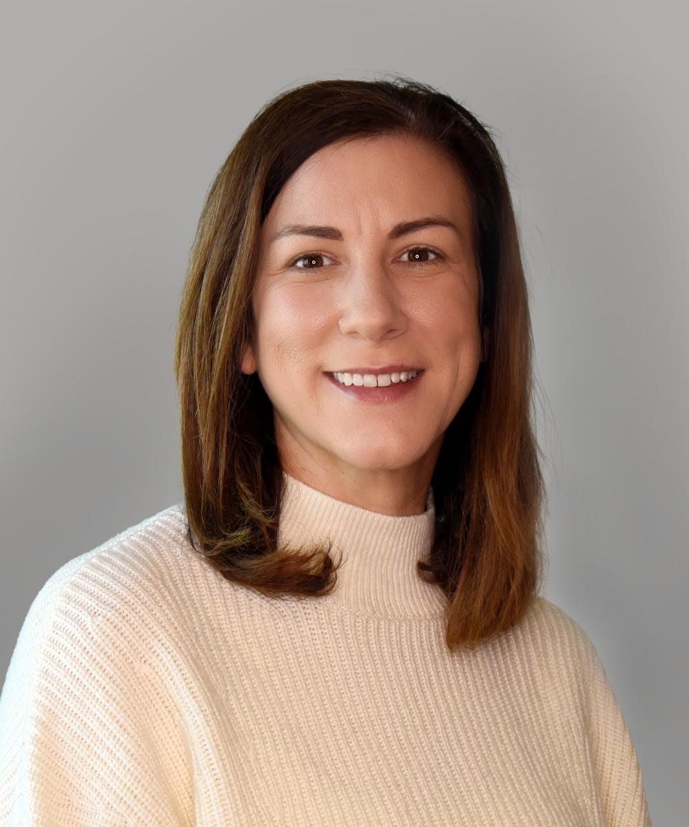Headshot of Elizabeth Siesener, wearing a cream turtleneck, with a plain gray background