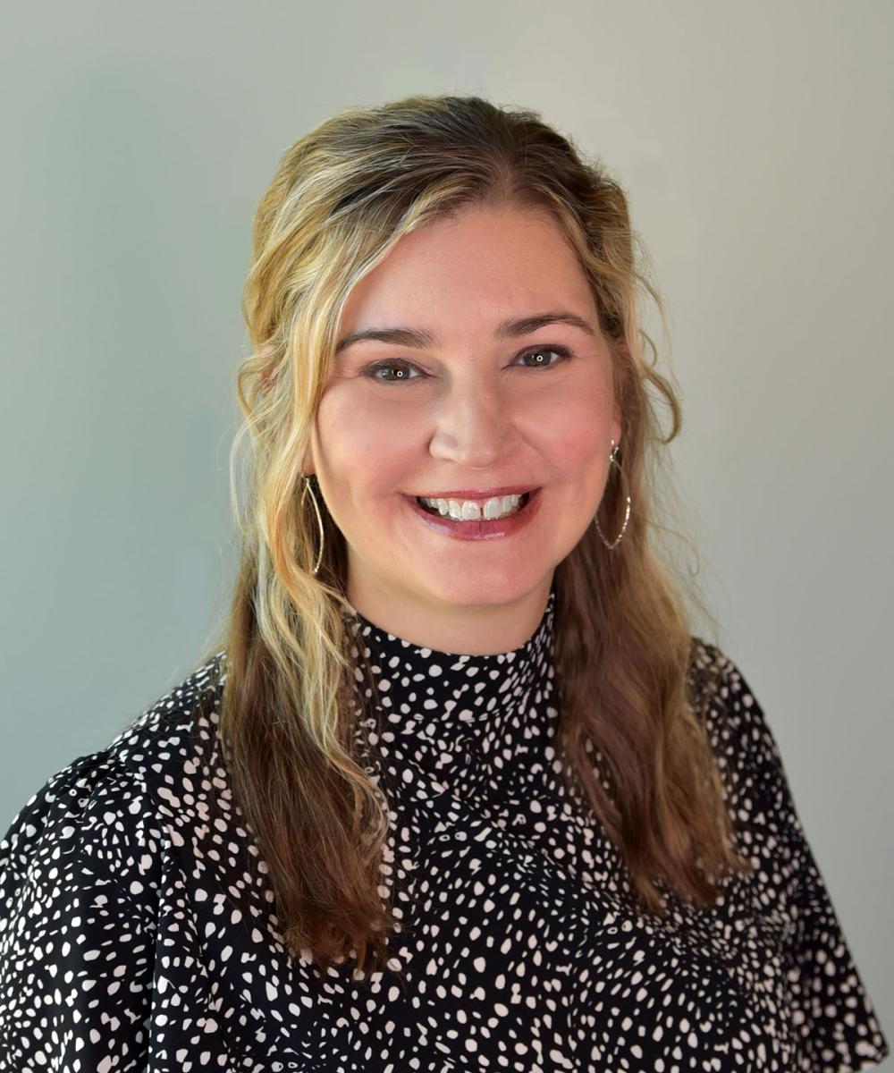 Headshot of Laurie Triplett-Wood, wearing a black and white patterned shirt, with a plain gray background