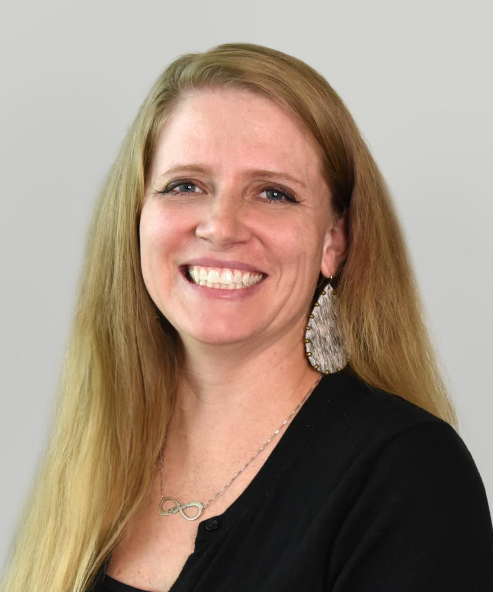 Headshot of Regina Crook, wearing a black shirt, with a plain gray background